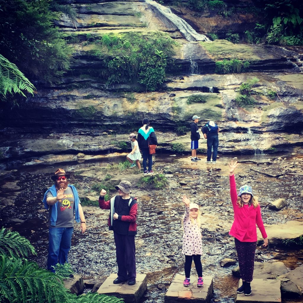 Autism family posing for photo on rocks at bottom of Katoomba Falls - positivespecialneedsparenting.com